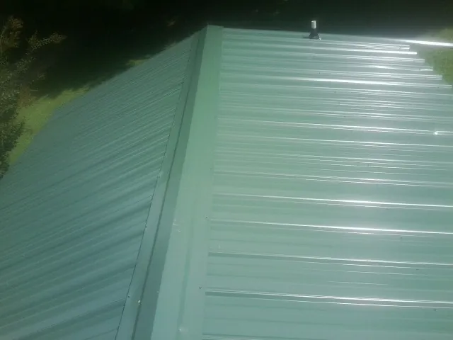 New green metal panels meeting at the ridge of a roof — Flat Roof Repair work by our crew in Buchanan Dam