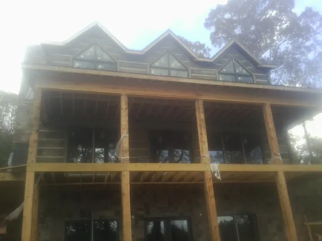 Dormers and porch framing on a large log home under construction — Roof Coating work by our crew in Buchanan Dam