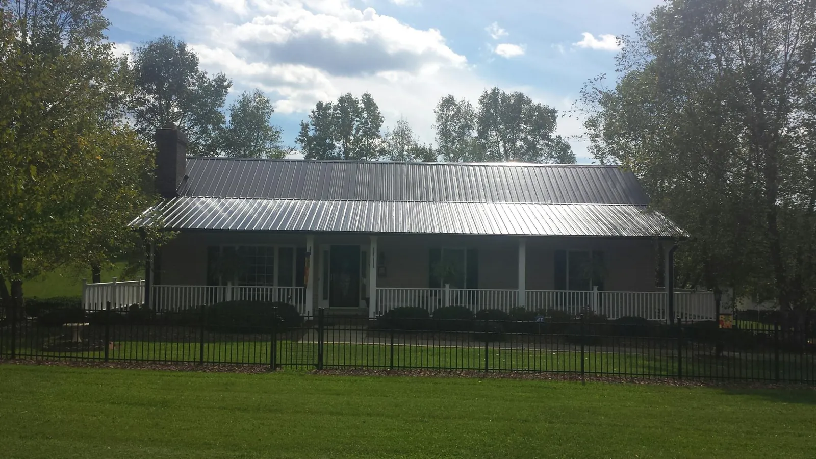 Gray metal roof on a brick ranch with a full width front porch — Gutter Guard Installation work by our crew in Buchanan Dam