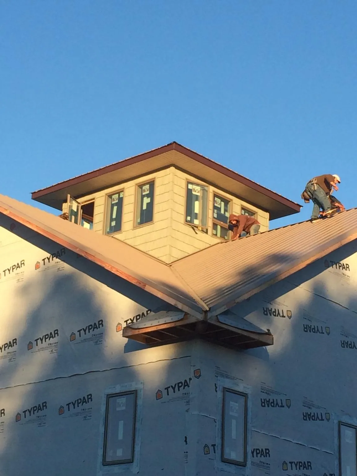 Roofers working around a rooftop cupola on a new metal roof at sunset — Roof Waterproofing in Buchanan Dam by Roofing Brothers